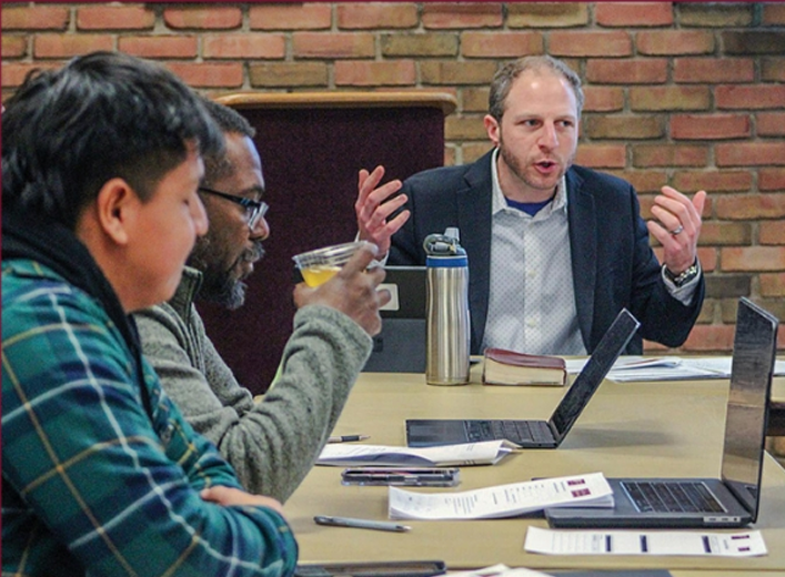 Matt Deutschman leading a triad peer advisory session with students and a business owner around the table.